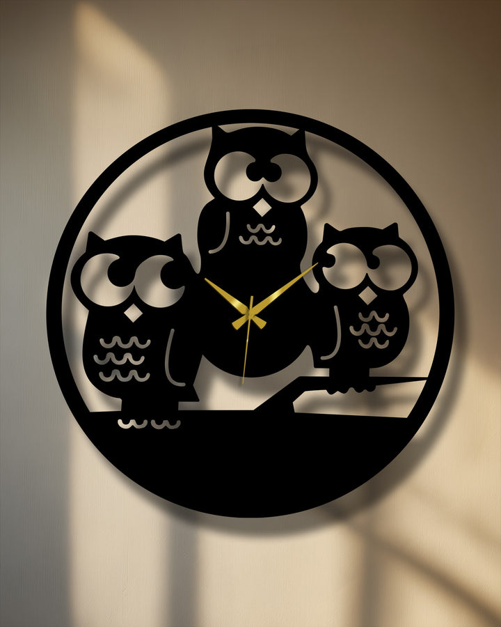 The stillness of the three owls silhouette metal artwork is gracefully depicted on this black clock, casting gentle shadows.