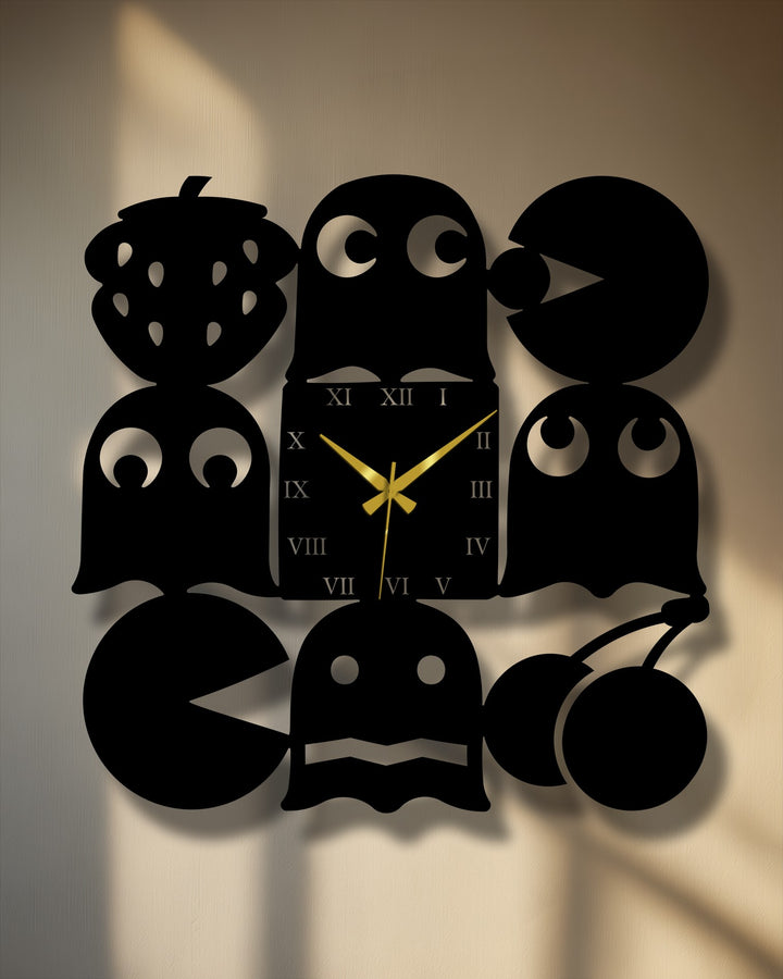 The foreground detail reveals intricate black silhouettes of Pac-Man, a ghost, and cherries from the decorative metal art wall clock.