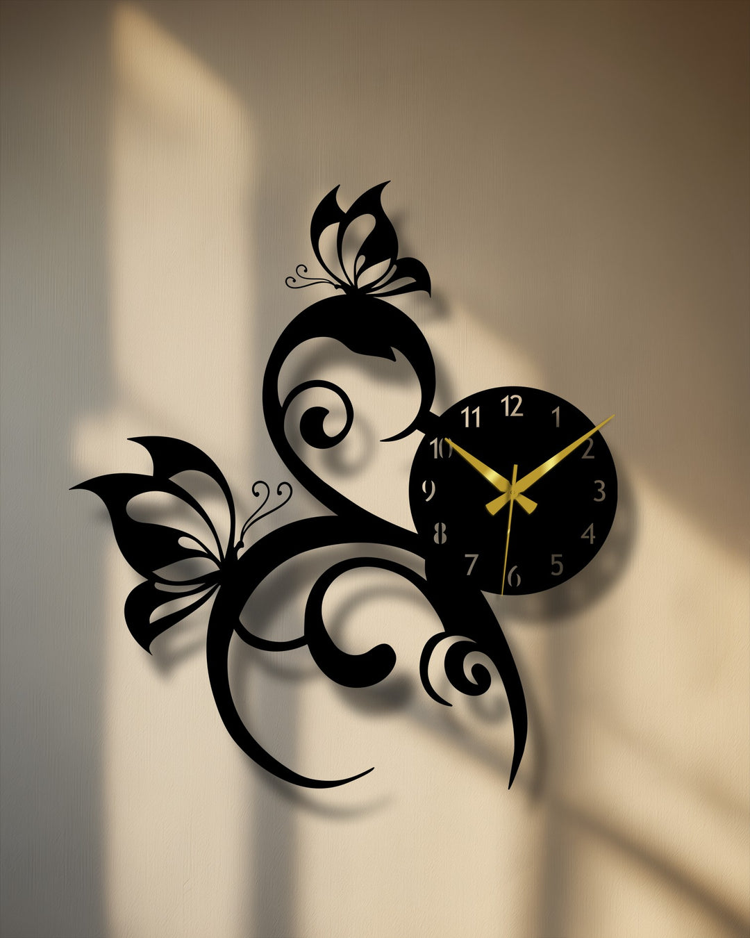 With moderately saturated tones, this elegant Butterfly Vine Metal Wall Clock showcases decorative metal art against a textured beige wall illuminated by soft sunlight.