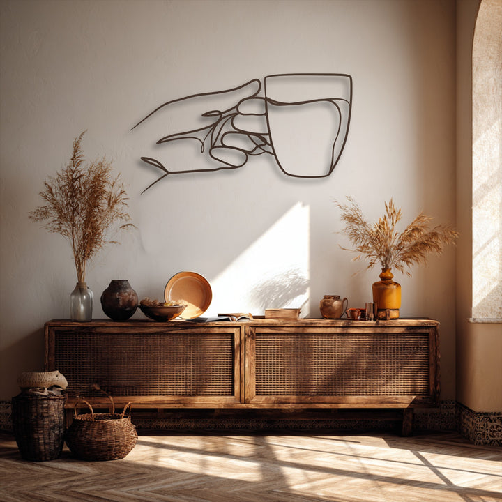 The shifting transition of warm wall tones to bright light highlights the dark minimalist hand holding cup unique metal wall art.