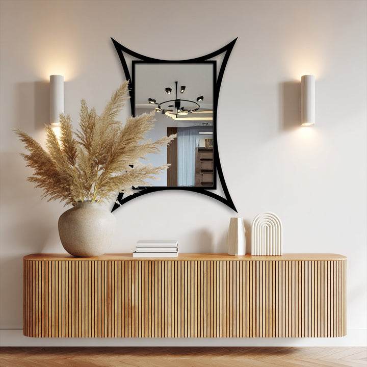 Curved metal frame of a modern, sculptural decorative mirror makes a bold and loud statement above a wooden console in a naturally lit room.