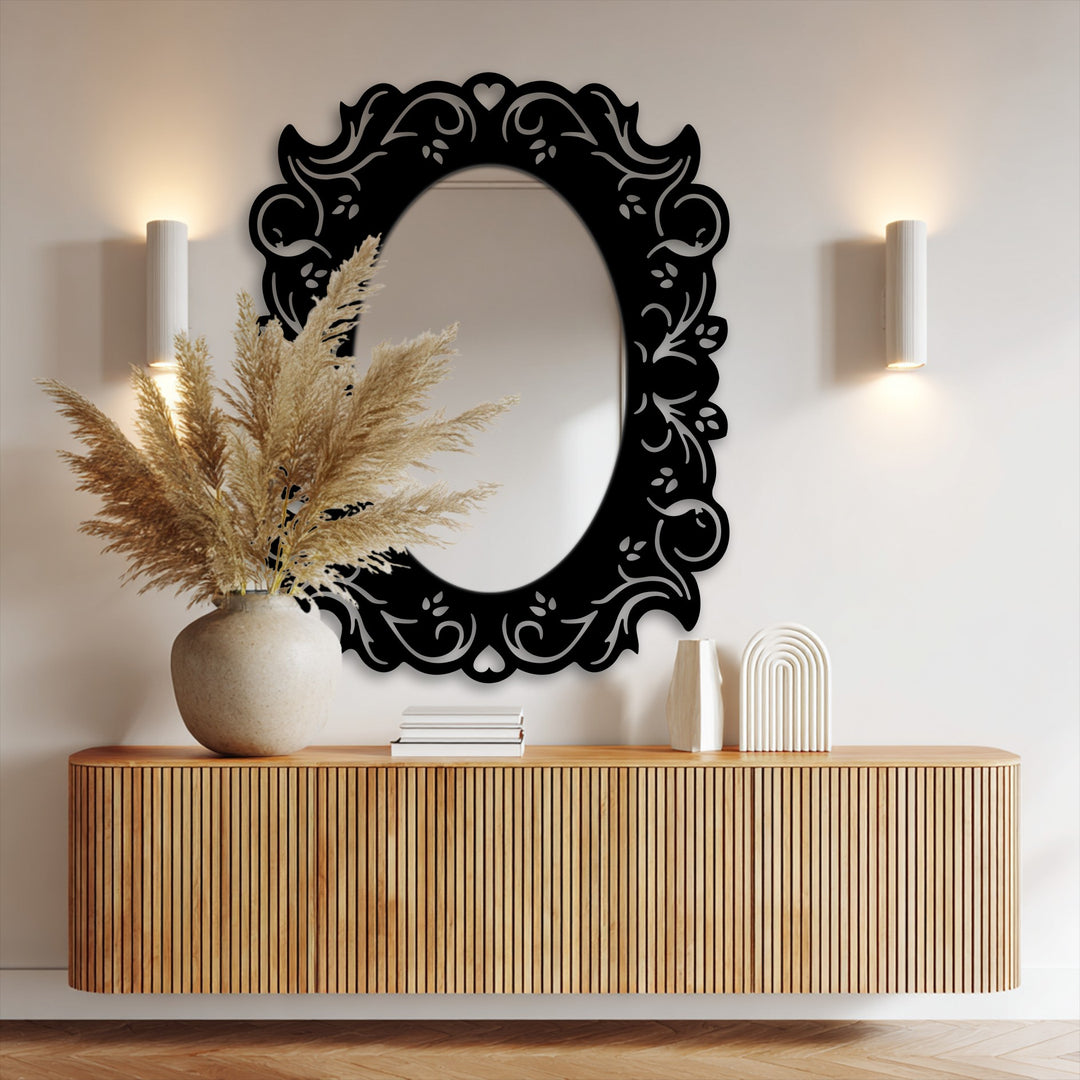 Striking color contrast highlights the black metal art for wall frame against the bright wall, accentuating the oval romantic floral design and its mirrored surface.