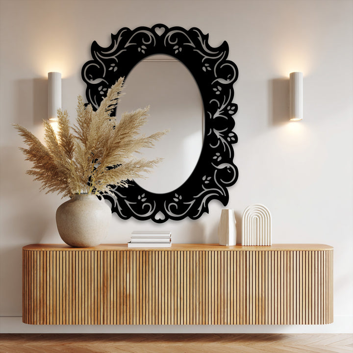 Striking color contrast highlights the black metal art for wall frame against the bright wall, accentuating the oval romantic floral design and its mirrored surface.