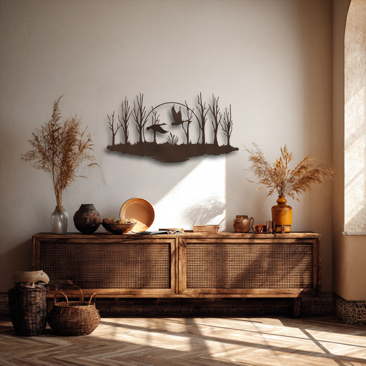 The decorative metal art piece creates depth with foreground reeds, layered trees, flying birds, and a central moon silhouette.
