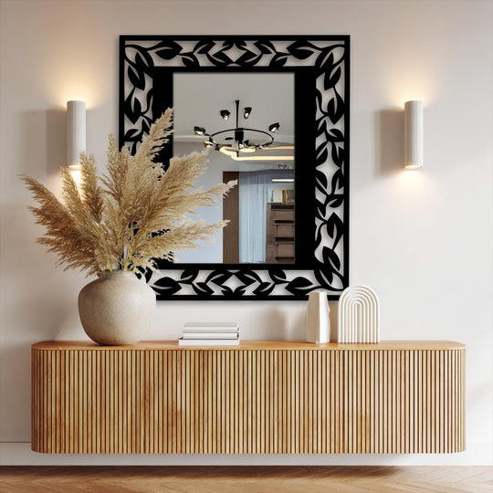 Feathery pampas grass in a vase softens the reflections in the leaf pattern frame, creating a delicate contrast to the unique metal wall art mirror.