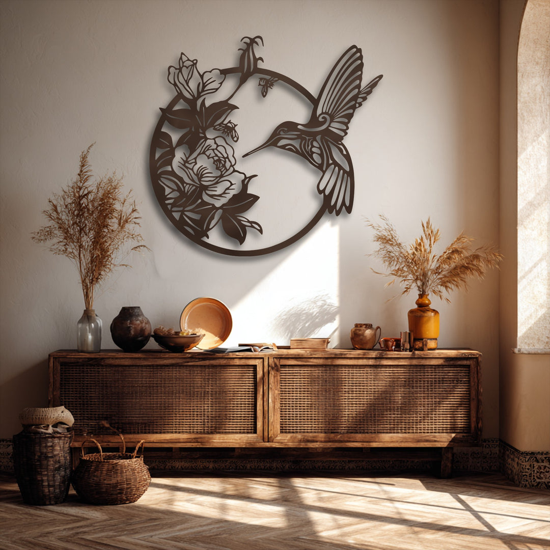 A circular metal wall decor piece, designed for vertical orientation, depicts a graceful hummingbird surrounded by blooming flowers.