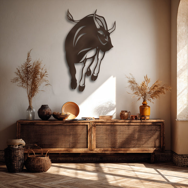 Subtle plaster wall texture enhances the smooth charging bull silhouette metal artwork, alongside a textured cane console and woven baskets.