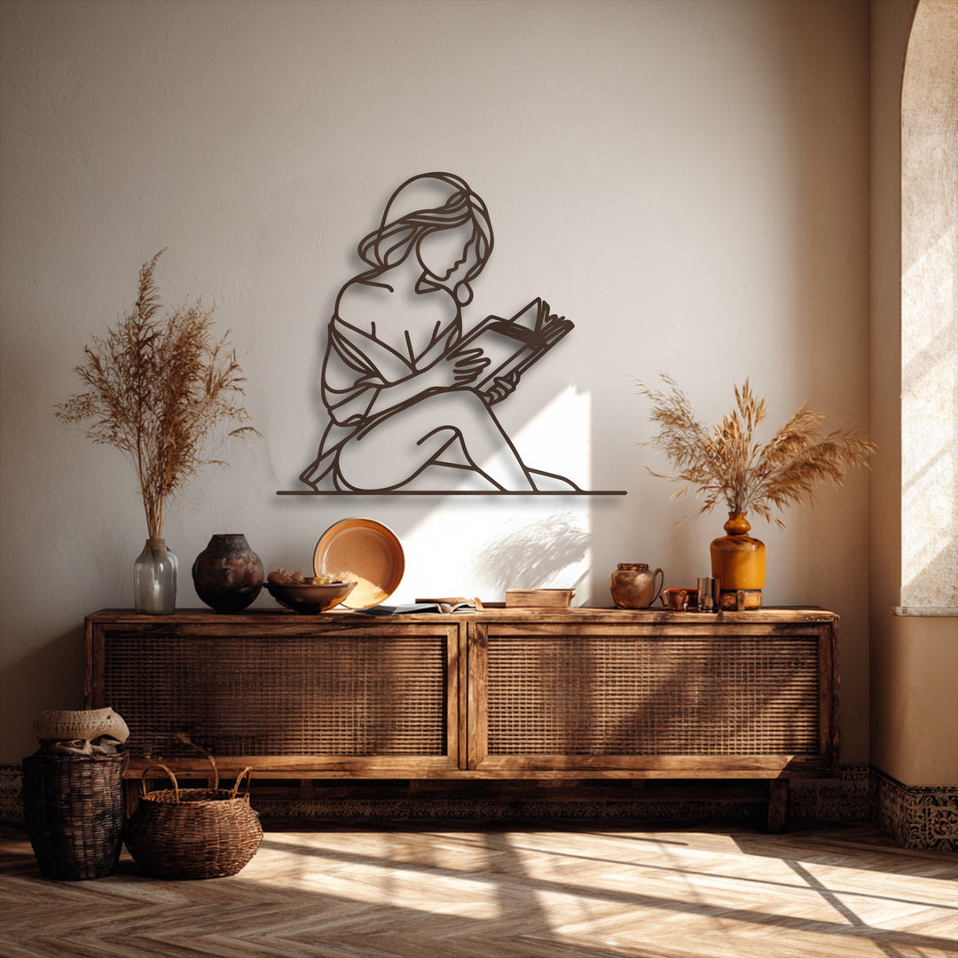 Negative space thoughtfully sculpts the serene outline of a woman reading, creating a compelling piece of decorative metal art.