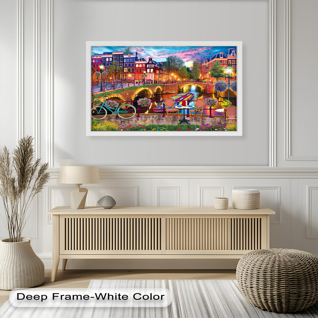 A vibrant framed wall art of Amsterdam’s iconic canals, colorful buildings, and charming riverside café, illuminated by warm evening lights.