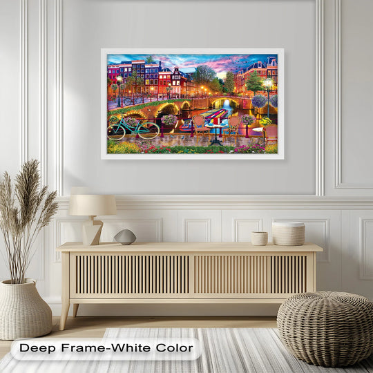 A vibrant framed wall art of Amsterdam’s iconic canals, colorful buildings, and charming riverside café, illuminated by warm evening lights.