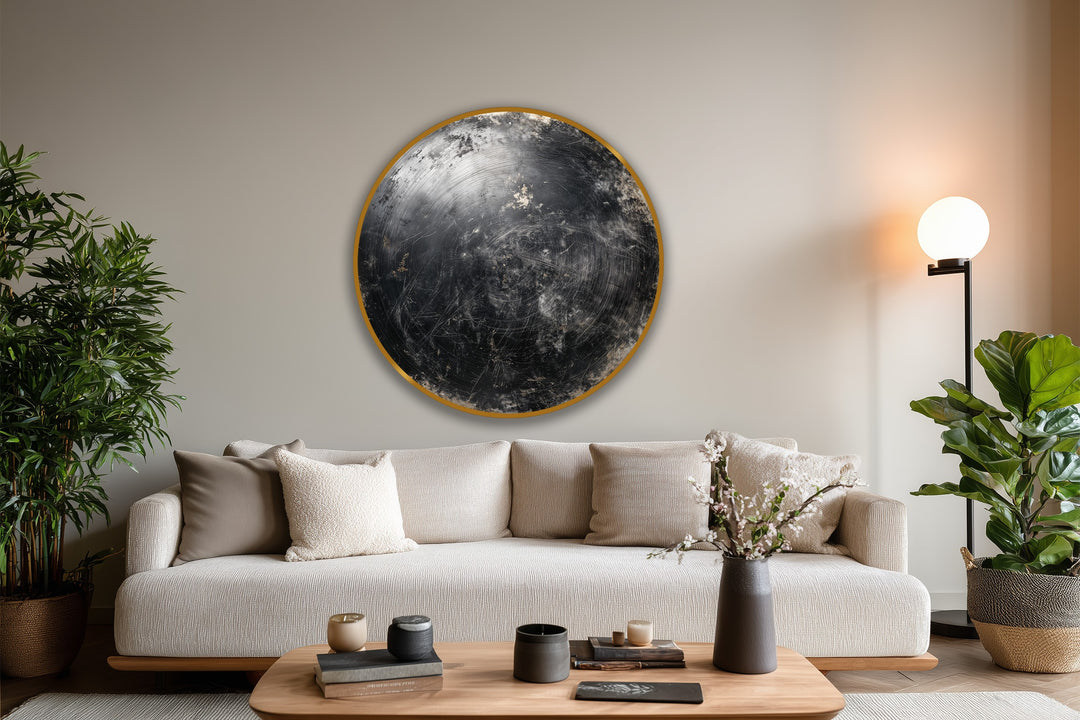 Negative space accentuates the dark, distressed textures of the round 'Midnight Orbit' oil painting art prints, framed in gold above a neutral sofa.