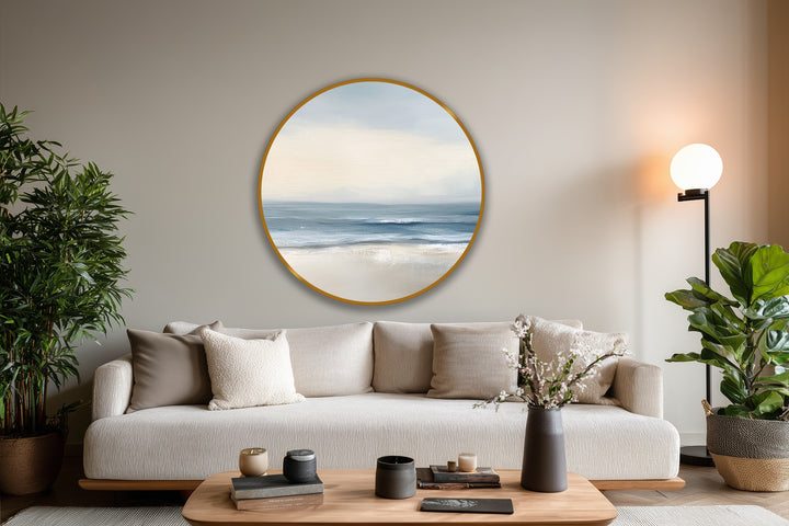 Neutral tones of the background complement the soft, minimalist coastal round oil painting art depicting a serene beach scene with gentle waves.