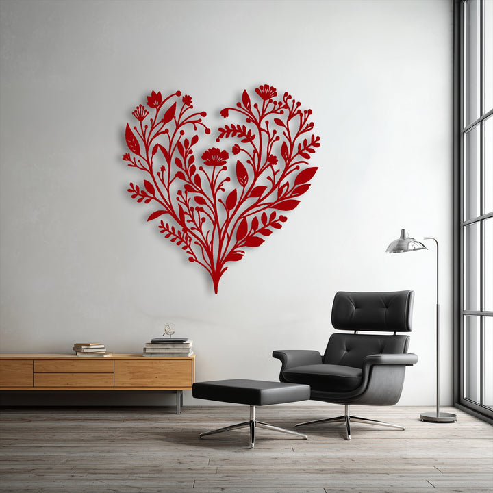 The organic forms of intricate red botanical heart metal wall decor feature flowing floral patterns and elegant leaves on a white wall.