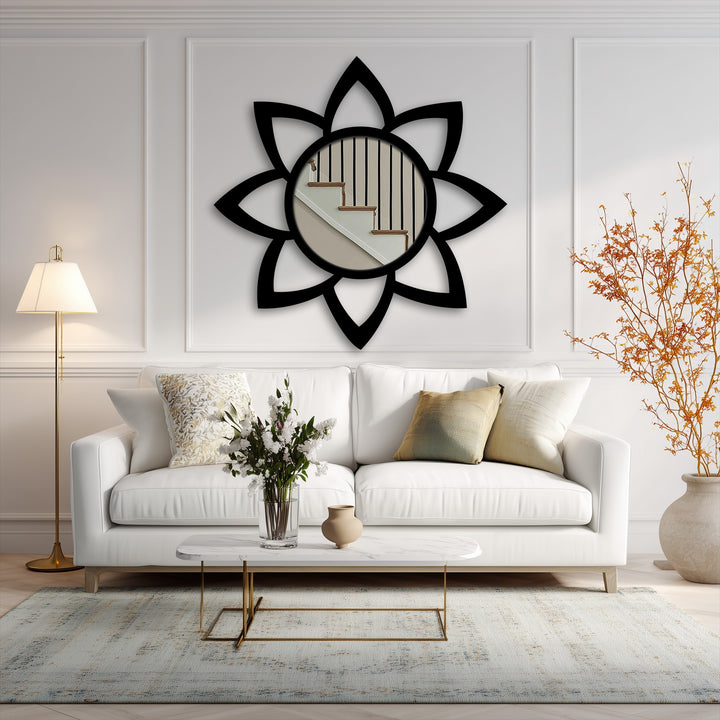 The stillness of a petal floor mirror, framed in black, reflects a bright stairwell in an elegantly modern and unique metal wall art piece.