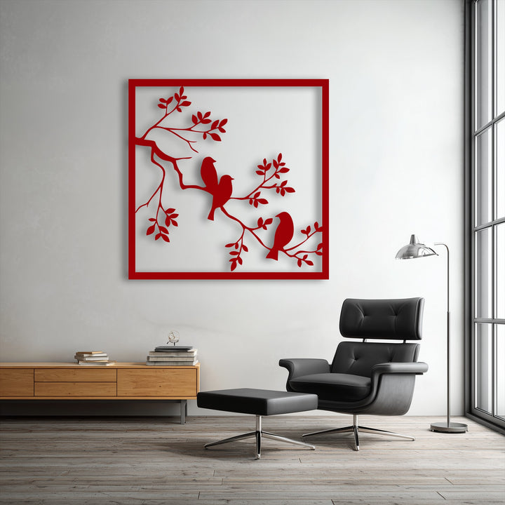 The strong geometric lines of the red framed metal wall decor showcase three birds perched on a tree branch silhouette.