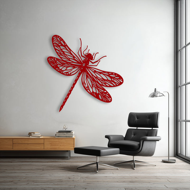 Luxurious black leather upholstery of the armchair and ottoman complements the unique metal wall art of an elegant red dragonfly, creating a soft contrast.
