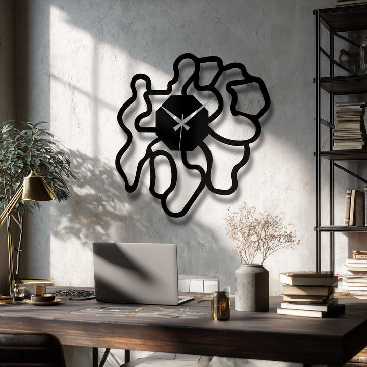Stillness captures the bold, geometric black shape of a modern abstract organic metal wall clock, creating a compelling, artistic display of unique metal wall art against the textured wall.