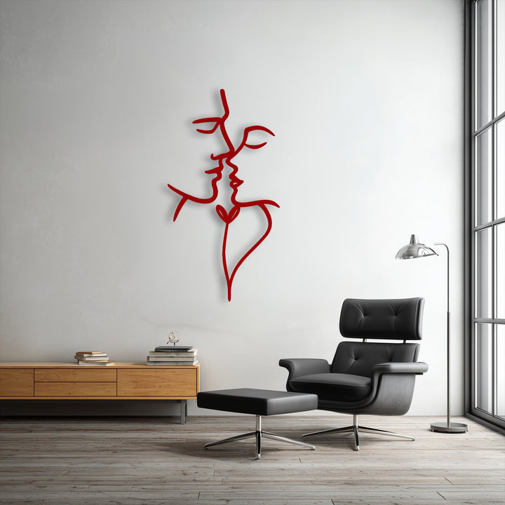 The plush black leather armchair and ottoman provide a soft contrast to the striking red Unity Line abstract face metal art for wall.