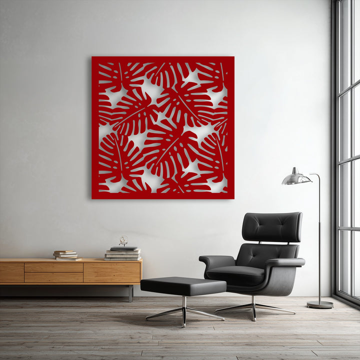 The vibrant red tropical monstera leaf pattern, a striking piece of modern metal wall decor, commands attention on the bright wall.