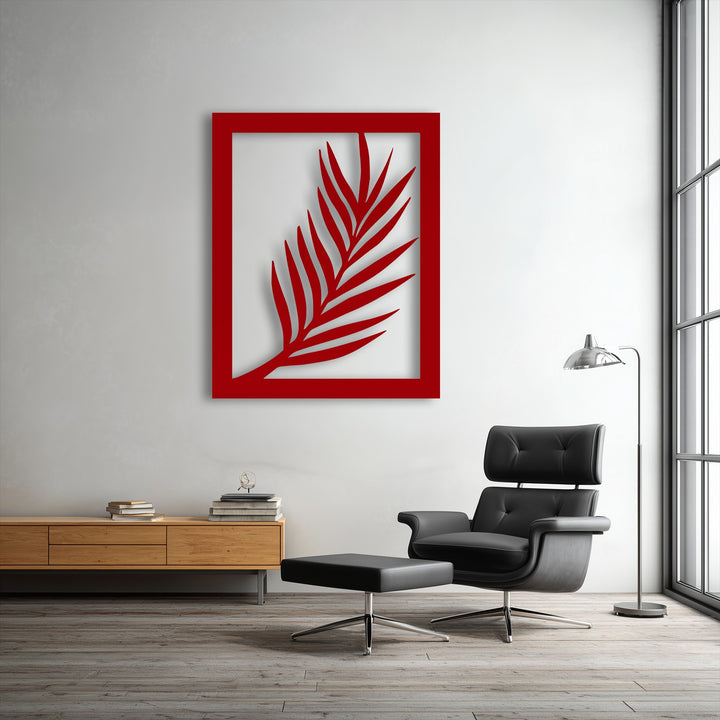 A vertically oriented rectangular red palm leaf metal artwork displays a minimalist botanical silhouette framed against a white wall.