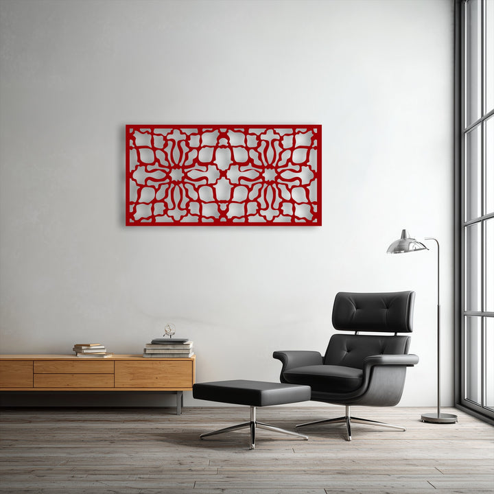 The vibrant red ornamental geometric decorative metal art sharply contrasts with the crisp white wall, defining a distinct color transition.