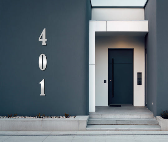 Showcasing the vertical metal art for wall that displays modern address numbers, centrally positioned on the exterior of a home with minimalist design.