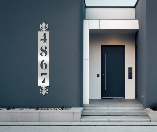 The realistic detail showcases the intricately designed vertical metal artwork featuring ornate address numbers with decorative accents, bringing sophisticated style to any home exterior.