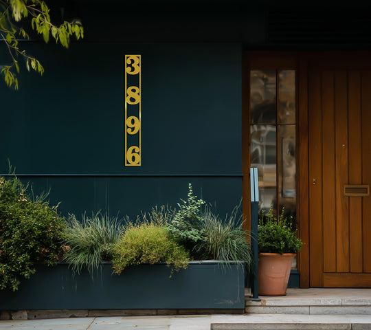 Showcasing the layering effect, the metal house number frame displays unique metal wall art with vertically stacked address numbers against a dark exterior wall.