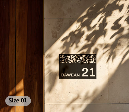 Negative space highlights the address sign's decorative metal artwork, contrasting leaves against the light stone and casting leafy shadows on the facade.