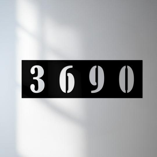 The darkest area outlines the unique metal wall art of the modern address numbers in a horizontal display.