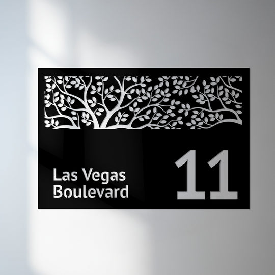 Layers of metal art for wall create depth in this modern house number plaque, showcasing a decorative tree design above the street name.