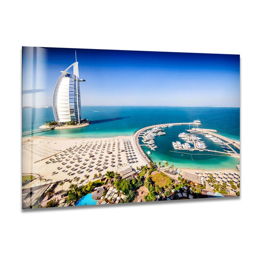 Dramatic color contrast highlights the azure sea and golden sands in this aerial view of Dubai’s Burj Al Arab and marina, a striking example of best glass art.