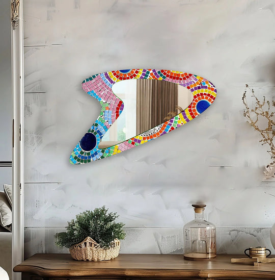Horizontally oriented, the uniquely shaped pink mosaic glass wall mirror features an asymmetrical design, reflecting modern wall mirrors style in its colorful tilework.