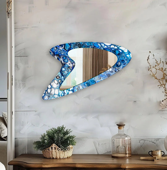 An asymmetric mirror with a blue bubbles modern abstract design a glossy glass frame and vibrant blue and white hues on a wall