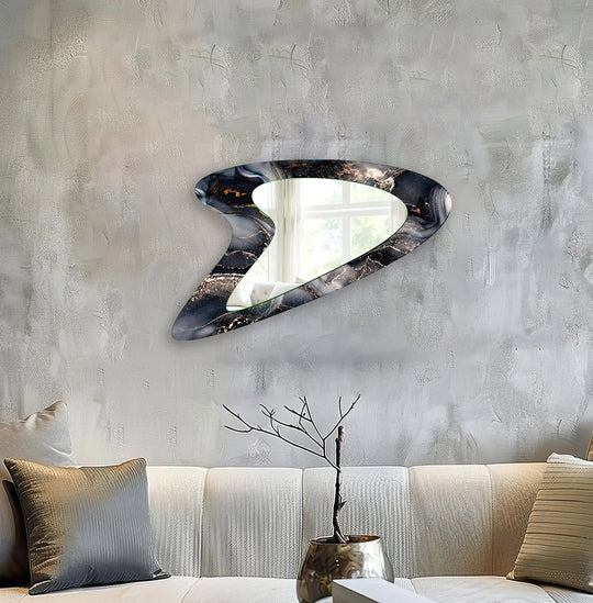Cool color temperature highlights the grey watercolor asymmetrical framed wall mirror reflecting a window with natural light.