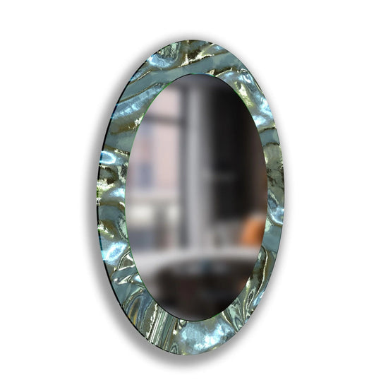 Detailed foreground shows the textured, metallic frame of this oval framed wall mirror, reflecting light with a captivating and abstract elegance.