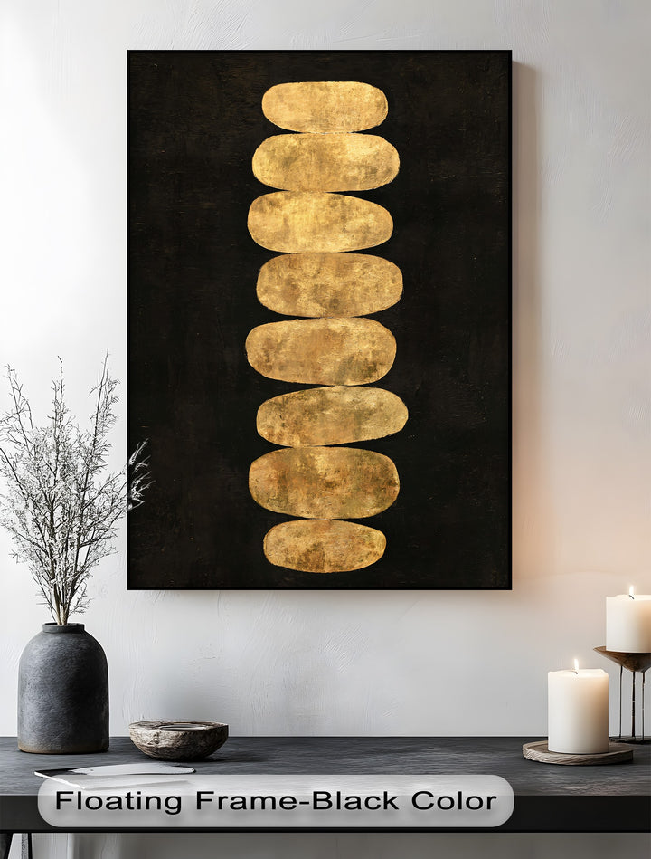 Foreground shows the golden balance stones canvas pictures creating minimalist zen wall art with a stark black background on a smooth, dark surface.