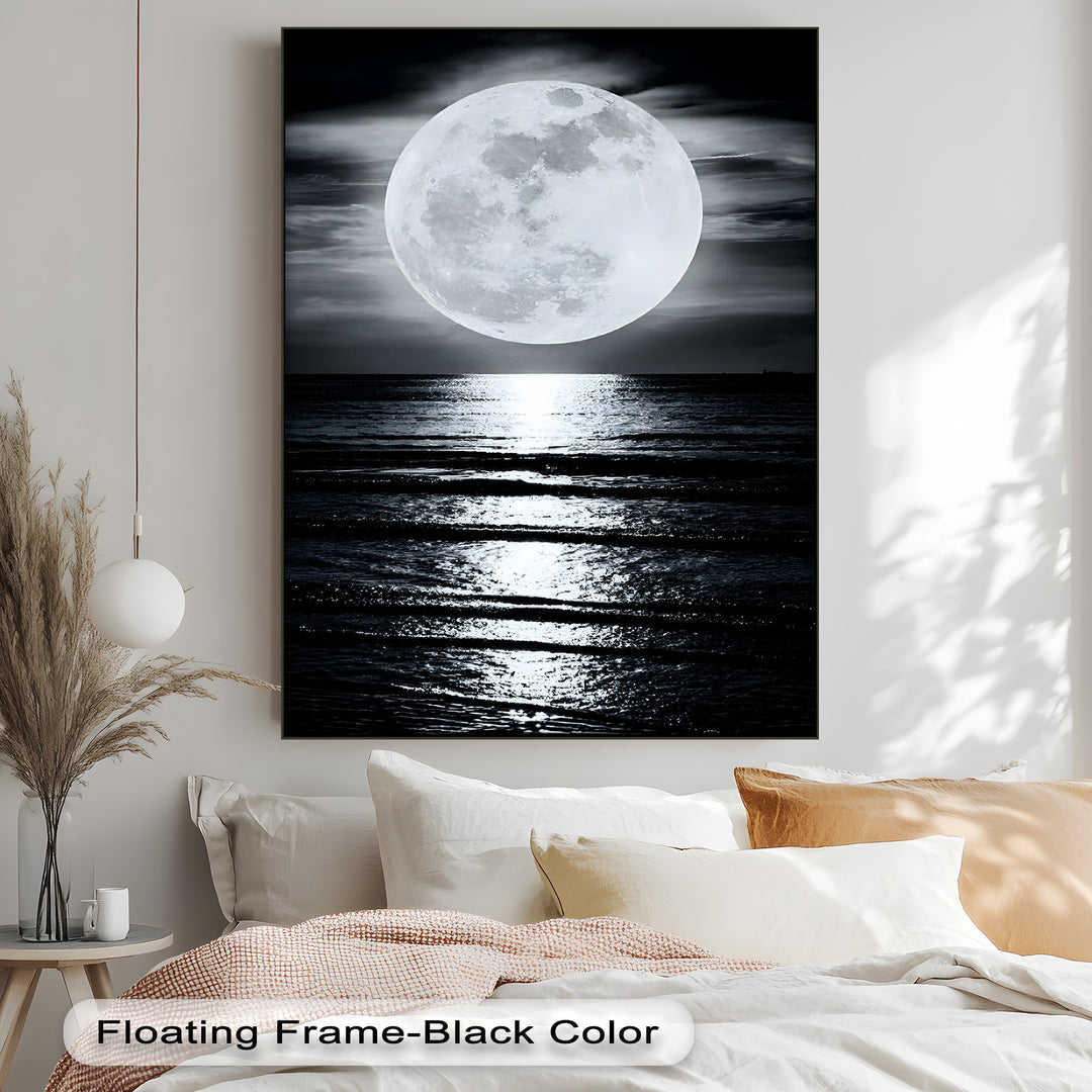 Plush white pillows and a soft, textured blanket provide a cozy foreground for the serene moonlit ocean reflection hanging canvas.
