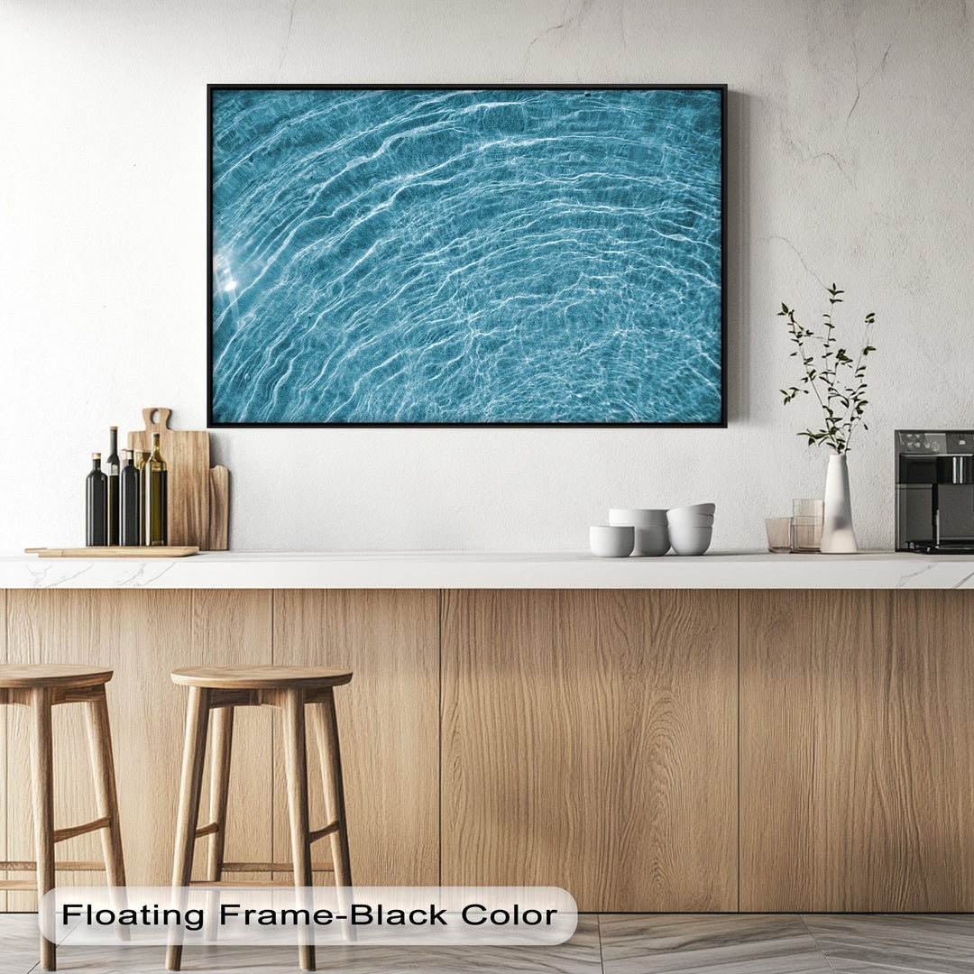 The expansive white wall and light countertop create a clean, minimalist negative space for the striking blue water ripple canvas painting.