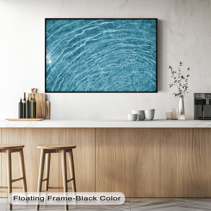 The expansive white wall and light countertop create a clean, minimalist negative space for the striking blue water ripple canvas painting.