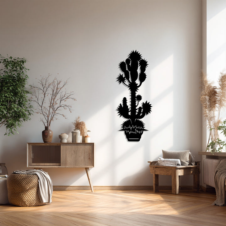 The organic forms of this black metal wall decor create a silhouette of a spiky desert cactus, casting shadows on the wall for a unique botanical display.