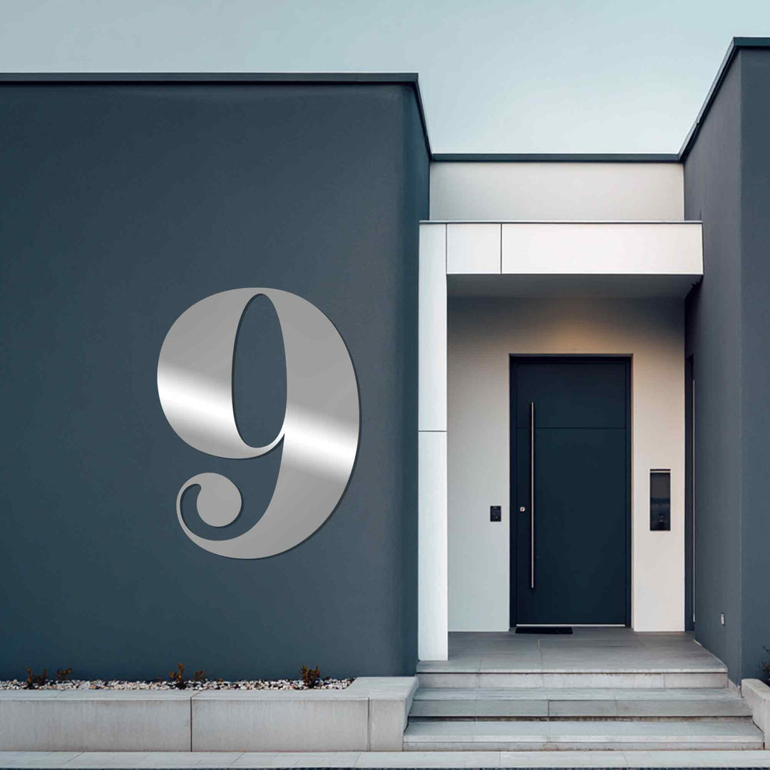 Juxtaposing geometric elements create a striking contrast in this metal wall decor showcasing a vintage-style metal house number against the clean lines of the modern architecture.