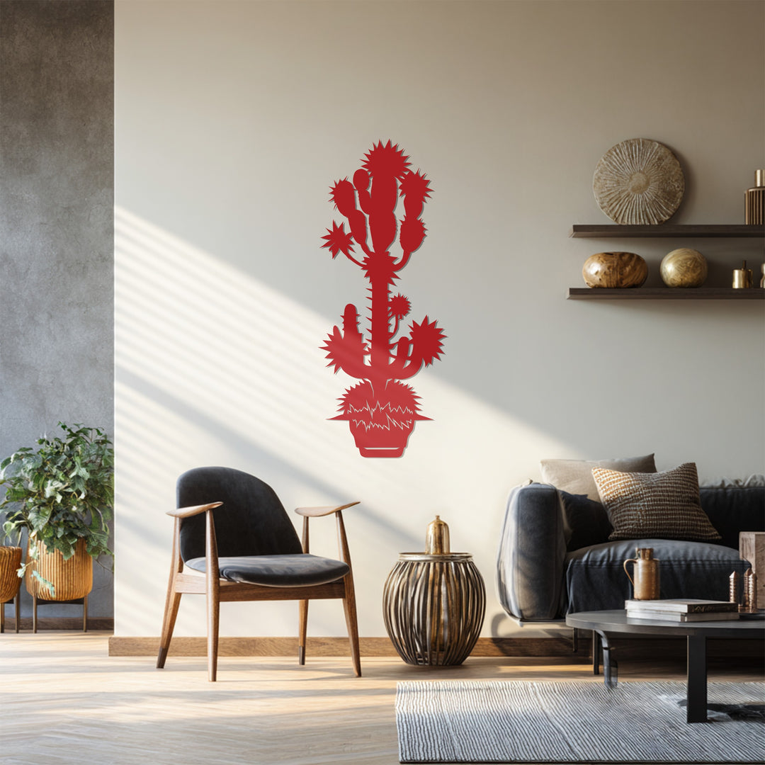 The wall transitions from the gray concrete to the warm beige, framing this decorative metal art piece depicting a spiky desert cactus in a bright red hue.