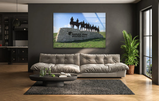 The soft, upholstered sofa provides a comforting contrast beneath the 'Dodge City' home decor glass wall art depicting the iconic landmark.