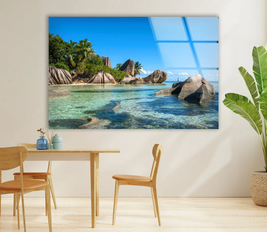Bright, clear reflections dominate this tropical rock coast scene showcased as a stunning tempered glass wall art print of a crystal blue ocean.