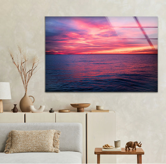 Tempered glass showcases the vibrant pink ocean sunset horizon, offering a durable and lustrous finish perfect for modern home decor in this seascape wall art.