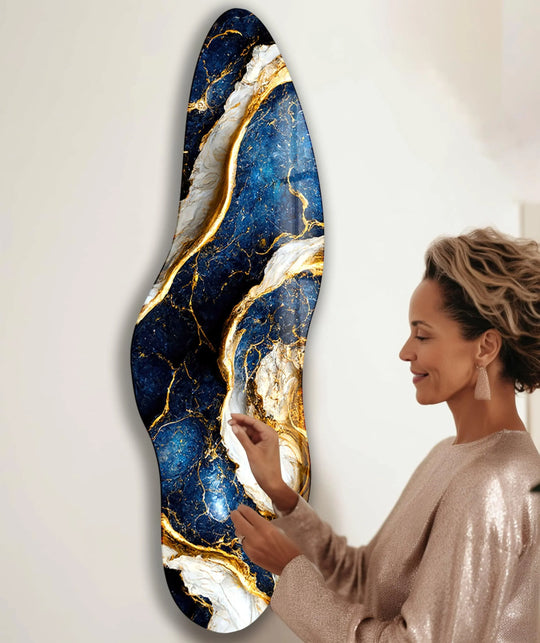 A woman's profile looks at the negative space surrounding a dramatic navy blue and gold abstract print wall art.