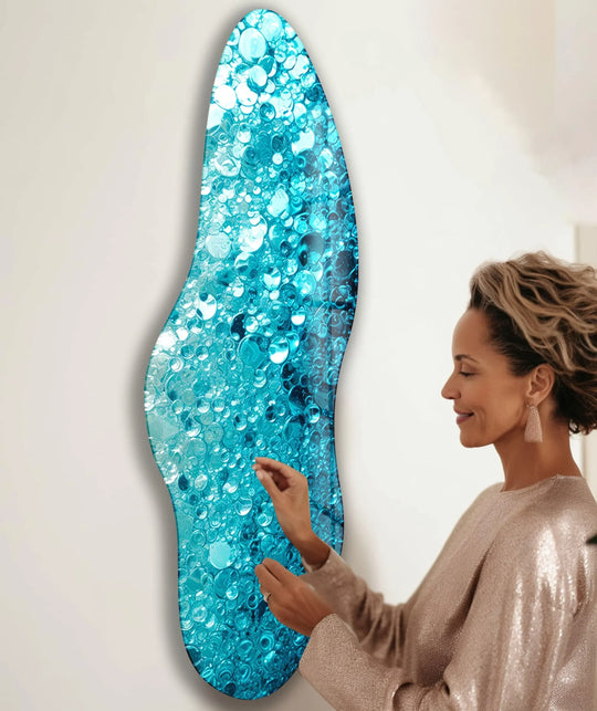 A woman touches a unique irregular asymmetrical water design glass wall artwork with turquoise bubbles.
