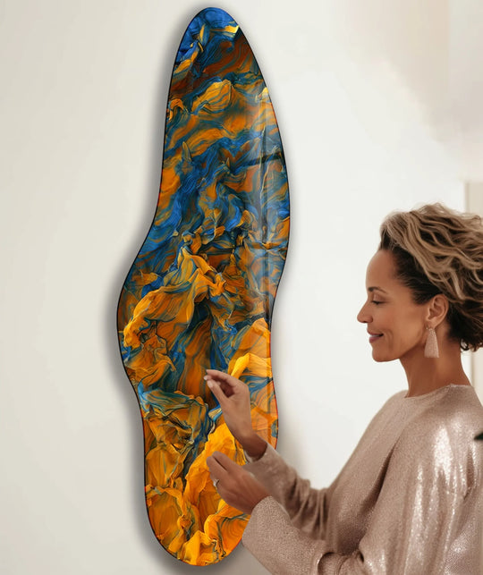 A woman admires a piece of best glass art with a realistic, detailed abstract design of swirling orange and blue hues.