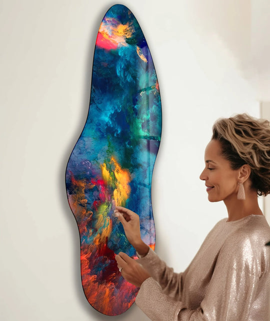 A woman touches a glass print wall art, showcasing a vibrant transition of colors from deep blues and greens to fiery oranges and reds.